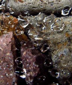 Close-up of rain drops on a spider web with river rocks underneath